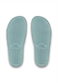 Lysblå gummiflip-flopsåler med et struktureret bølgete mønster og logo; har afrundede kanter for komfort og greb.