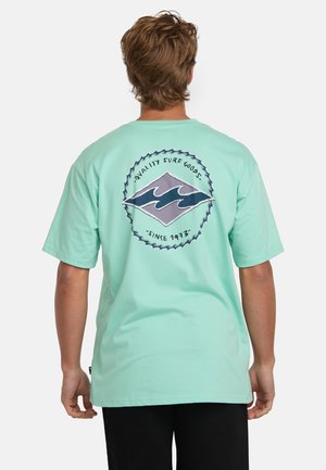 Mintgrønt bomulds t-shirt med et cirkulært trykt design på ryggen med bølger, omgivet af tekst og en dekorativ kant.