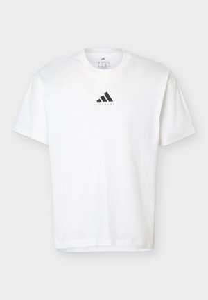 Mann mit dem Rücken zur Kamera, trägt ein weißes Adidas-Shirt mit dem Schriftzug „I'd rather be running“ und einer Grafik eines Laufschuhs, kombiniert mit roten Shorts.