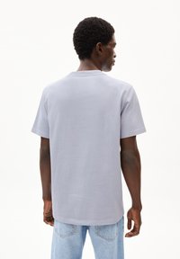 Graues Baumwoll-T-Shirt mit Rundhalsausschnitt und kurzen Ärmeln, mit einem lockeren Schnitt und einer glatten Textur, kombiniert mit hellblauen Jeans.