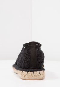 Espadrillas in crochet nero con parte superiore testurizzata, fascia elastica sul tallone e suola in juta naturale. Il design presenta un retro aperto per una maggiore traspirabilità.