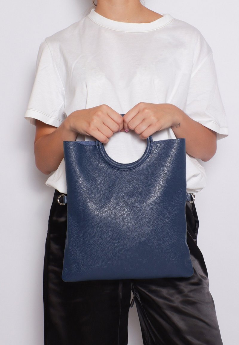 Borsa tote in pelle blu navy con manico arrotondato, caratterizzata da una superficie testurizzata e assenza di parti metalliche visibili. La borsa è rettangolare e piatta.