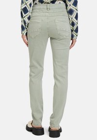 Jean slim fit vert clair avec une texture lisse, dotés de deux poches arrière et de surpiqûres prononcées à la taille et aux coutures.