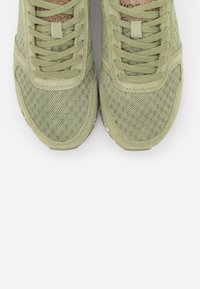 Scarpe da ginnastica verdi con una tomaia in rete testurizzata e dettagli in suede. Presentano lacci piatti e una soletta imbottita. Suola in gomma bianca visibile.