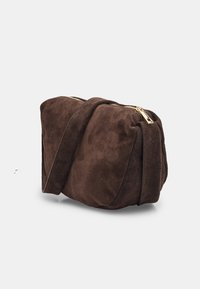 Borsa a mano in suede marrone con una texture morbida, forma arrotondata e dettagli in metallo dorato sulla zip. Presenta una sola tracolla regolabile.
