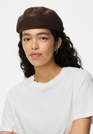 Brun filt beret med rund form og en glat tekstur. Båret med en ensfarvet hvid t-shirt, der fremhæver et minimalistisk design.