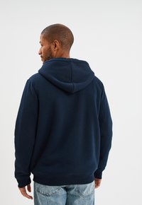 Sudadera azul marino con forro interior texturizado, puños elásticos y dobladillo. Presenta una capucha con cordón y un ajuste relajado, fabricada en tejido suave.