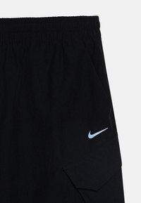 Črne cargo kratke hlače z elastičnim pasom, teksturiranim materialom, stranskimi žepi in svetlo modrim Nike logotipom.