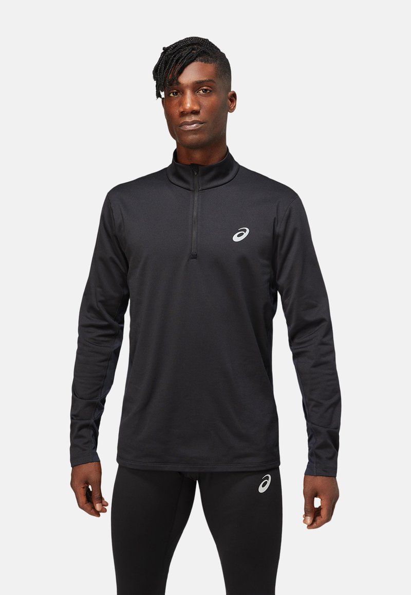 Black long-sleeve athletic shirt with a quarter-length zip, featuring a reflective logo on the chest and a smooth, dry-fit material.