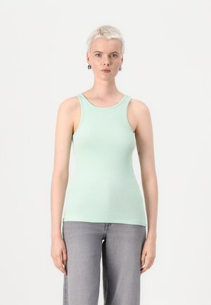 Lys myntegrønn ribbestrikket tanktop med scoop hals og tynne stropper, paret med grå vide jeans, på en enkel hvit bakgrunn.