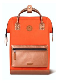 Sac à dos en tissu orange avec une poche avant en cuivre texturé, des accents en cuir, des poignées doubles et un patch logo circulaire. Compartiments zippés.