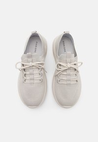 Light grey athletic shoes made of breathable mesh. Rounded toe, flat rubber sole, elastic lace design, and a pull tab on the heel.