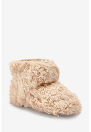 Chausson botte d'intérieur beige, duveteux et doux, avec un revers, conçu pour la chaleur et le confort.