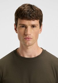Olivengrøn tekstureret crew-neck t-shirt med en tætsiddende pasform. Stoffet har et subtilt mønster og en glat finish omkring halsen.