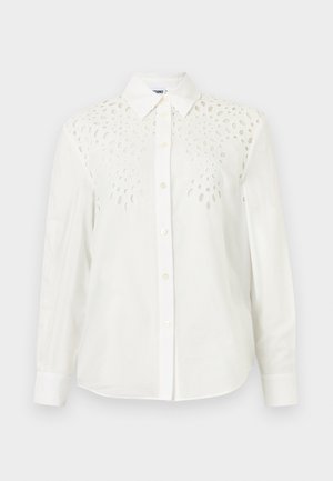 Camisa blanca de manga larga con botones, con cuello puntiagudo y patrones decorativos recortados en la parte superior delantera y los hombros.