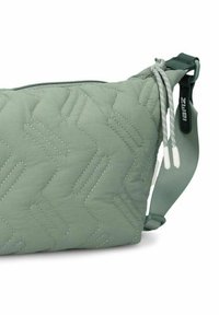 Grüne gesteppte Schultertasche mit Zickzacknähten, Reißverschluss und verstellbarem Riemen. Sie zeichnet sich durch eine glatte Textur und ein leichtes Design aus.