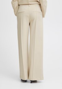 Beige wide-leg trousers made of a smooth fabric with a tailored fit, featuring two back pockets and a structured waistband.