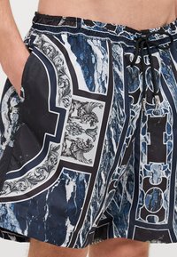 Plavkové šortky s modrým mramorovým vzorem a kontrastními černými a bílými akcenty. Elastický pas s tkaničkou, postranní kapsy.