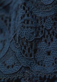 Mörkblått virktyg med intrikata mönster och öppna detaljer, som framhäver textur och lagerdesign.