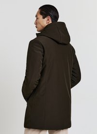 Parka marrone scuro con cappuccio, caratterizzata da una texture liscia, taglio dritto e tasche laterali, vista da dietro su uno sfondo chiaro.