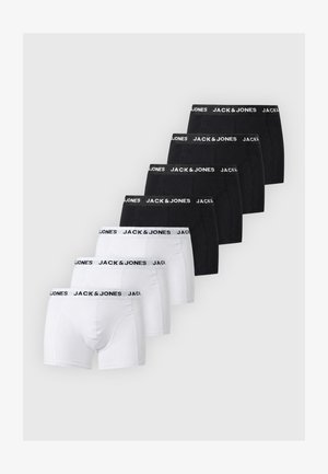 Hemdenloser Mann steht barfuß in schwarzen Jack & Jones Boxershorts vor einfachem hellem Hintergrund.