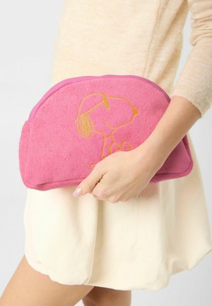 Personne tenant une pochette rose texturée avec un contour brodé de Snoopy portant des lunettes de soleil.