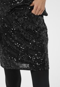 Fekete flitteres ruha textúrált felülettel és testhez simuló sziluettel. Rejtett zsebbel és sima anyaggal az alatta.