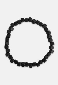 Juodas karoliukų vėrinys, kuriame yra kvadratiniai mediniai karoliukai su matinio paviršiaus apdaila, išdėstyti nuolatiniame apskritime. Nematomas užsegimas.