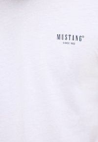 White cotton t-shirt featuring a small black "MUSTANG" logo with "SINCE 1932" underneath, smooth texture, short sleeves, and classic crew neck design.