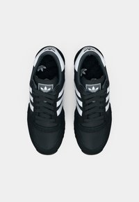 Pair of black Adidas sneakers with white stripes and logos, viewed from above on a white background.