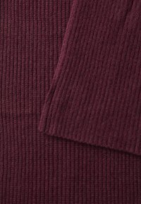 Bordeaux ribbeltricot stof met een zachte textuur, gekenmerkt door verticale lijnen en een iets losse weving, wat diepte in het uiterlijk creëert.