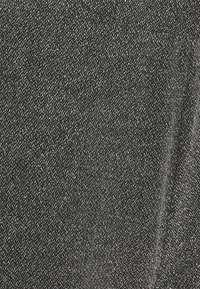 Czarna tkanina o fakturowanym wzorze, zawierająca przeplatane metaliczne nici dla delikatnego połysku. Gładka w dotyku, o średniej wadze, lekko się układa.