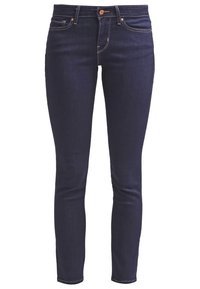 Jeans ajustados de mezclilla azul oscuro con una textura suave, diseño clásico de cinco bolsillos y costuras en contraste en las juntas.