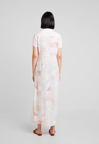 Maxi dress in lightweight fabric, featuring a multicolor geometric pattern with pink, red, and blue accents. Short sleeves and elastic waist.