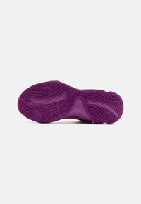 Lilla atletiske sko sål med en struktureret gummioverflade med riller for bedre greb, en unik form og Nike-branding.