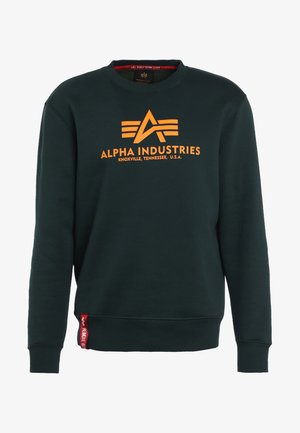 Donkergroene sweatshirt van zacht materiaal met een oranje "ALPHA INDUSTRIES" logo en accentlijnen aan de voorkant. Ribgebreide manchetten en onderrand.