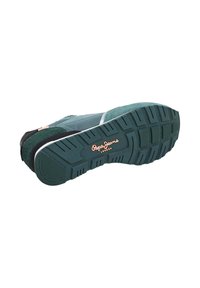 Sneaker verde in suede con accenti neri, suola in gomma testurizzata con profondi intagli e un logo in rilievo dorato sul lato.