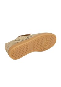 Baskets avec une tige en synthétique beige, design texturé et une sangle Velcro. La semelle en caoutchouc naturel présente un motif en losanges pour une meilleure adhérence.