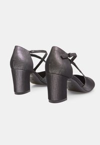 Black heeled shoes with a textured finish; crisscross straps and small bow accent. The heels are moderate in height and slightly chunky.