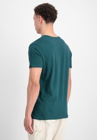 Teal kortærmet t-shirt med rund halsudskæring, lavet af et glat stof. Har et lille mærke på venstre ærme, tætsiddende design.