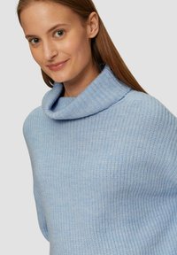 Hellblauer Strickpullover mit einem Schalkragen. Die Textur ist weich und gerippt, was ein gemütliches Aussehen und eine lockere Passform verleiht.