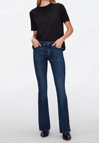 Black short-sleeve t-shirt with round neckline paired with dark blue flared jeans. The jeans have a smooth texture and slight fading.