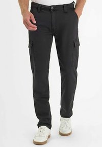 Zwarte cargobroek met een slanke pasvorm, voorzien van zijzakken en een knoopsluiting. Het materiaal lijkt stevig, met een gladde textuur.