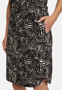 Černobílá sukně s motivem palmového listu, boční kapsou a zakřiveným lemem. Vyrobena z texturované, lehké látky.