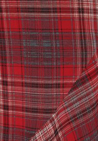 Tessuto tartan rosso caratterizzato da un motivo di strisce alternate in nero, bianco e grigio, con una superficie liscia e un aspetto tessuto.