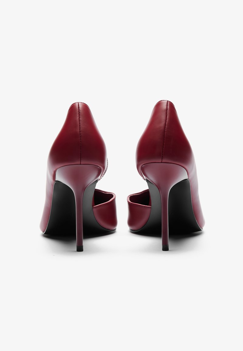 Scarpe con tacco alto in pelle bordeaux, con punta affusolata, tacco a stiletto sottile e design elegante. Schiena aperta e superficie liscia.