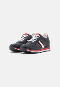Zapatillas deportivas con una parte superior en color marino, con textura perforada, acentos rojos y rayas blancas. Cuentas con cordones blancos y una suela de goma texturizada.
