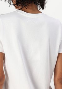 Hvid kortærmet t-shirt med rund hals, blød tekstur og et diskret "2NDDAY" logo broderet på ryggen.