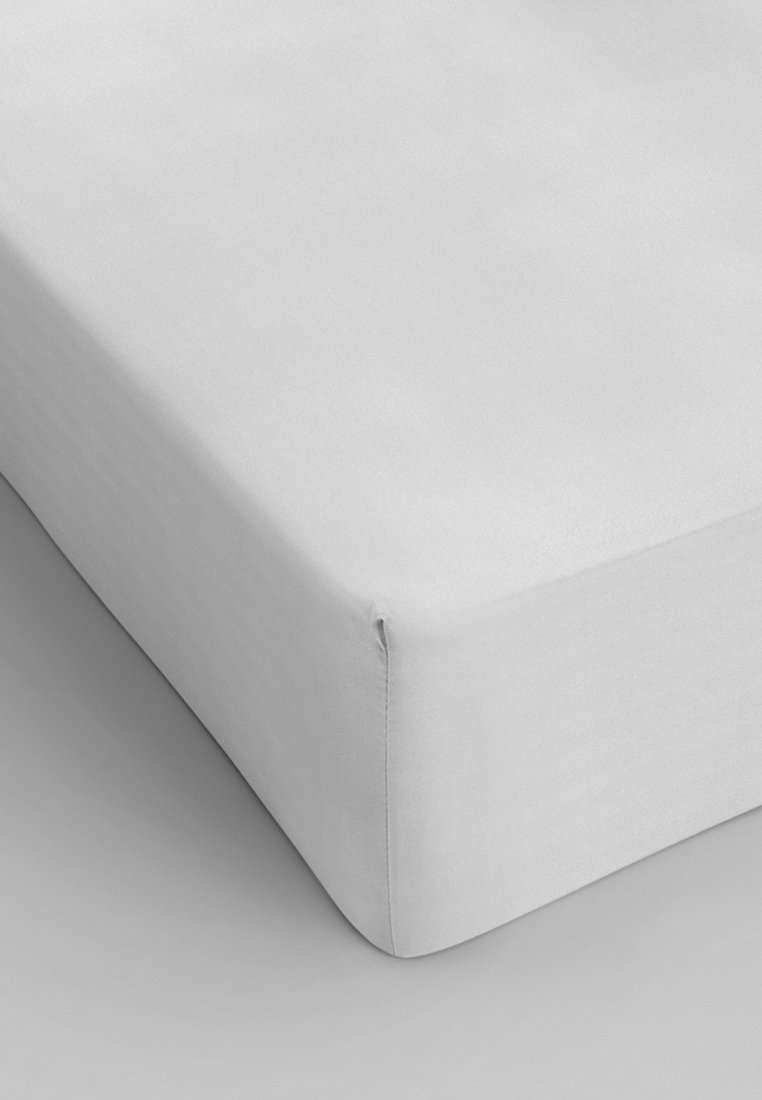 Housse de matelas blanche ajustée avec une texture lisse et des coins soigneusement cousus, conçue pour s'adapter parfaitement à un matelas.