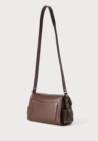 Brown leather shoulder bag with a rectangular shape, featuring a front pocket, adjustable strap, silver hardware, and contrasting stitching.